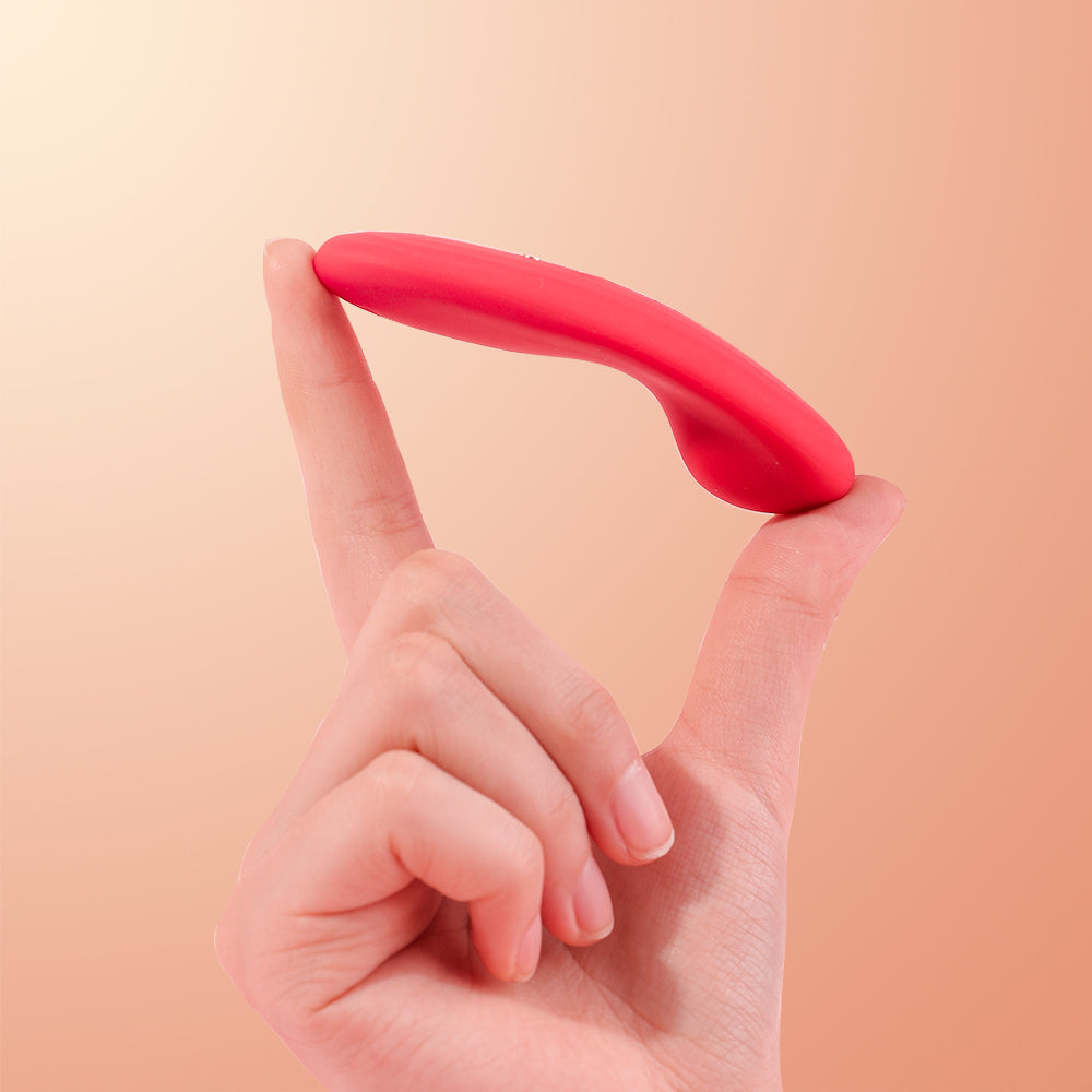 Red curved silicone vibrator attachment held between fingers