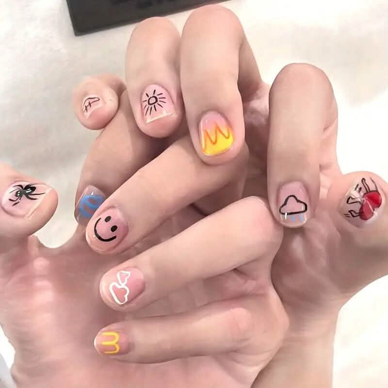 Decorated fingernails with cute doodle designs like hearts, smiles, and small symbols
