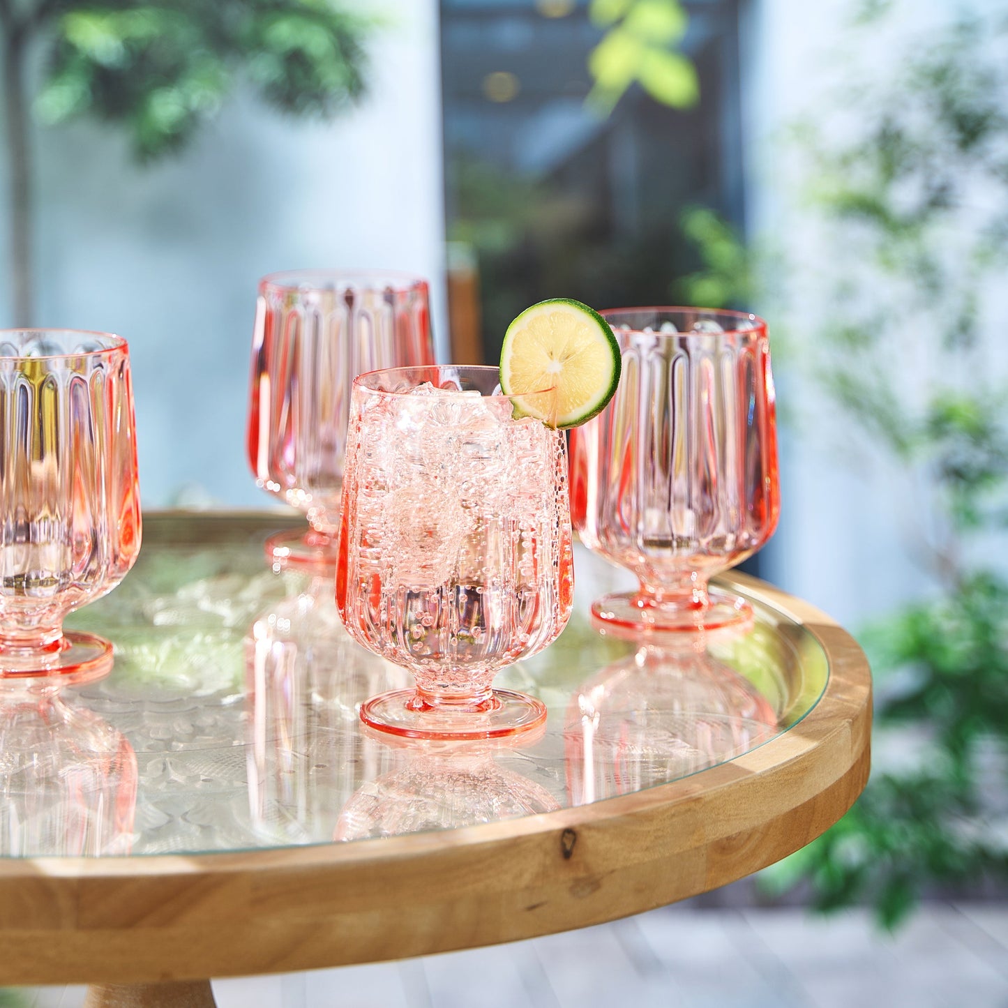 Rose-tinted ribbed acrylic wine goblet with stem and foot; lime slice on rim