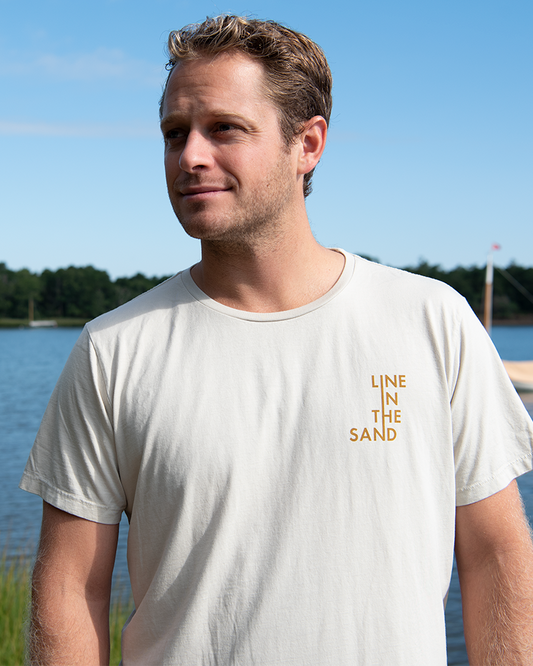 Sand unisex T-shirt with small orange “LINE IN THE SAND” text logo on the chest