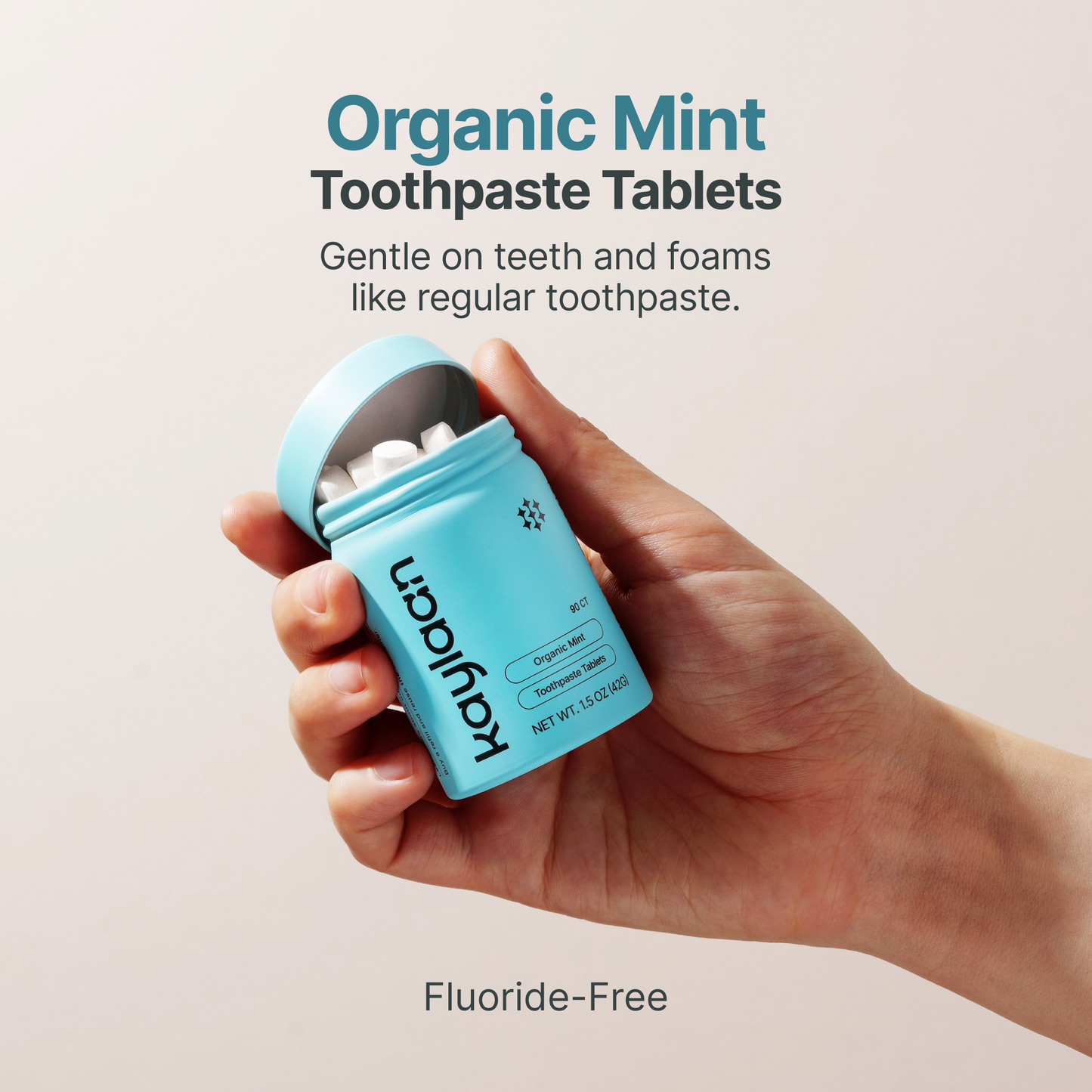 Hand holding organic mint toothpaste tablets jar in blue, fluoride-free