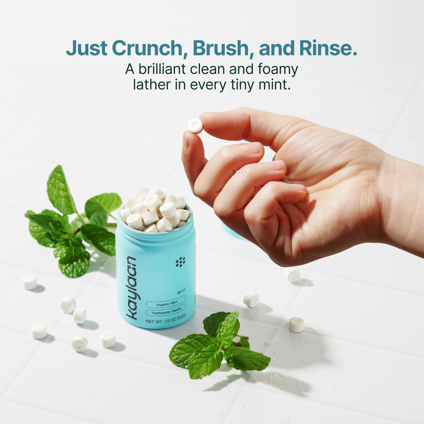 Hand dropping mint fluoride toothpaste tablet into blue canister