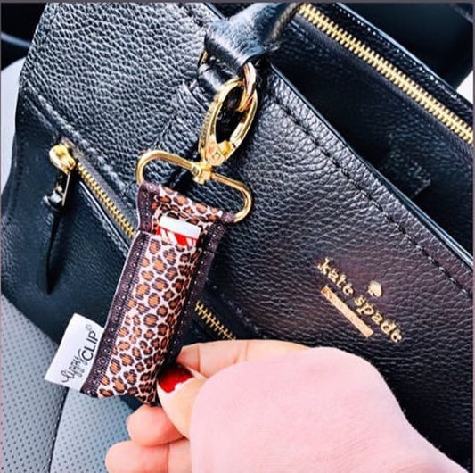 Leopard print key clip attached to a black handbag with 'kate spade' branding.