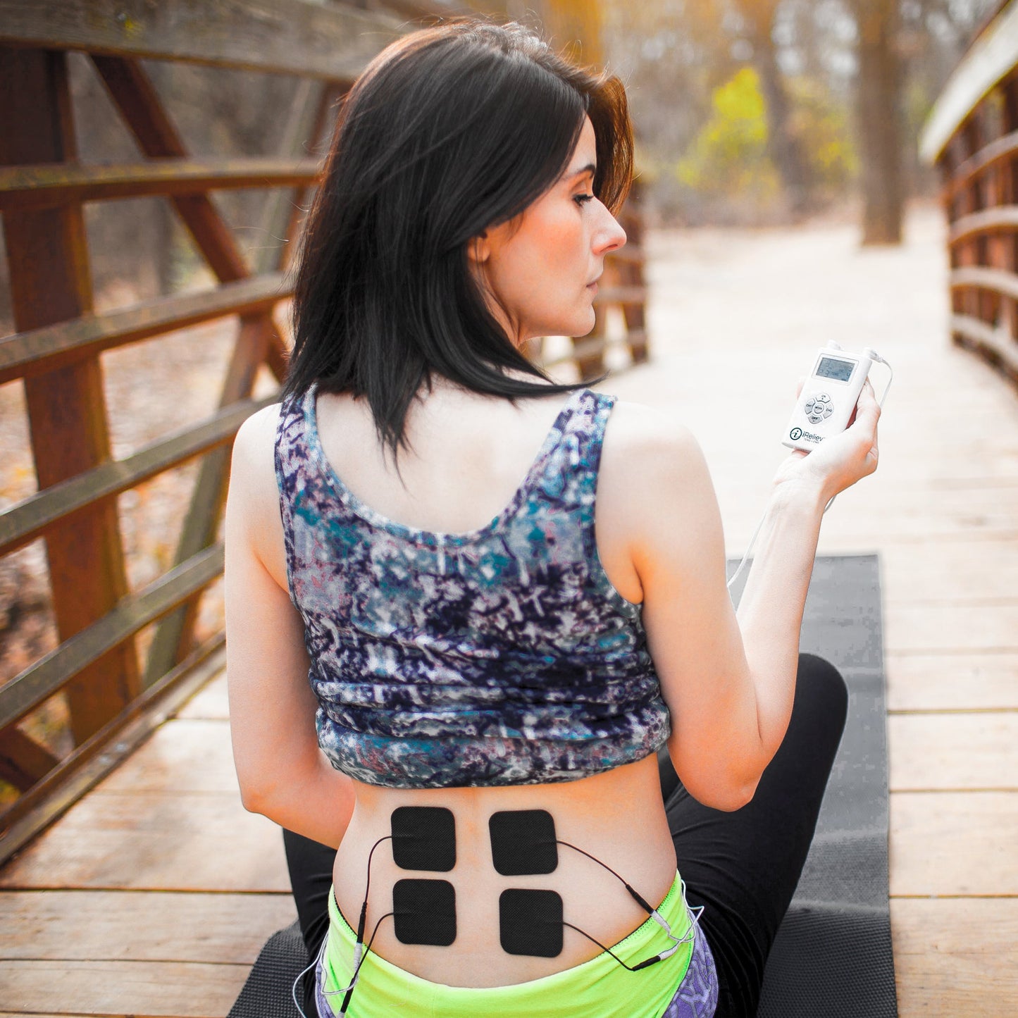 Black electrode pads attached to abdomen with thin cables for stimulation