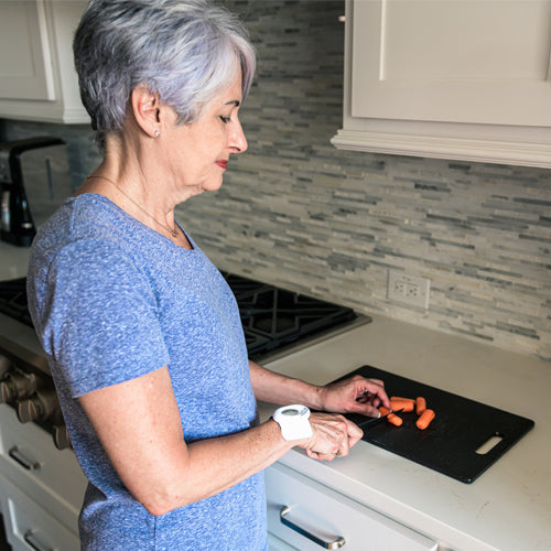 Pain relief patch controller and textured adhesive pad on arm in a kitchen