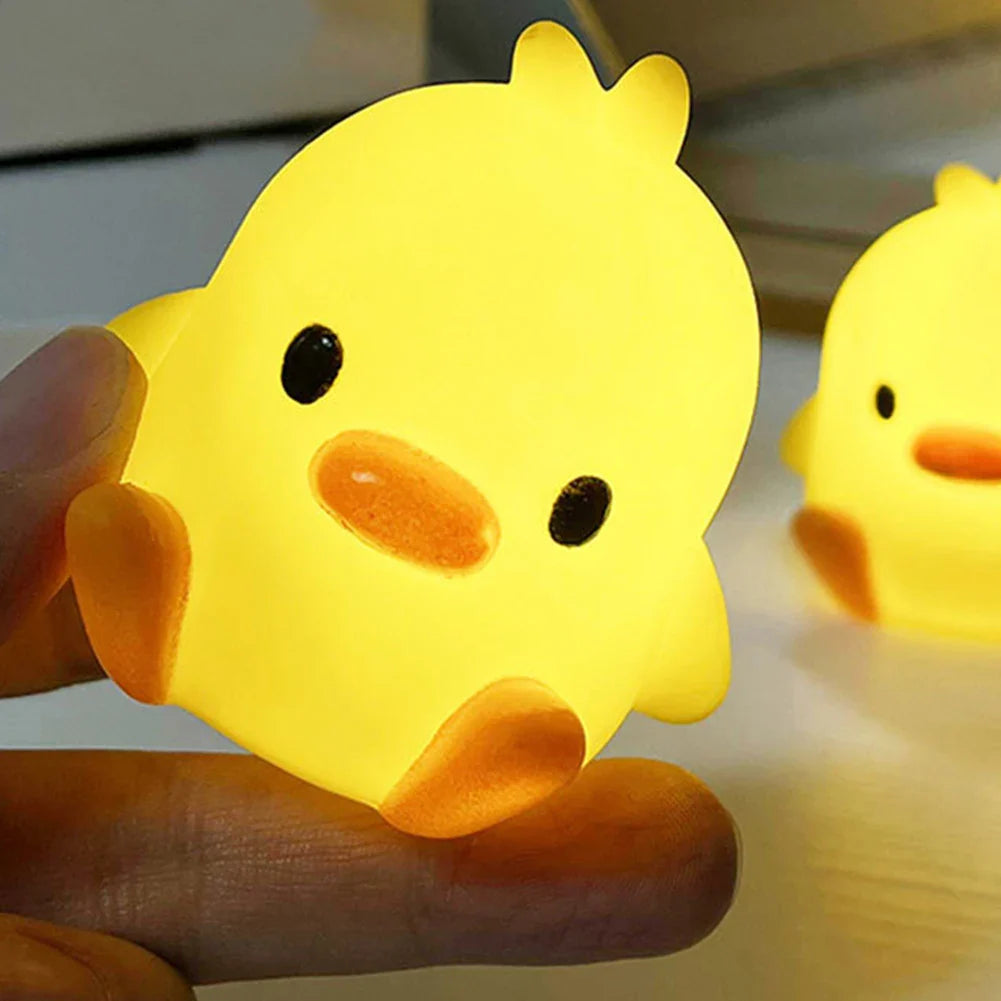 Close-up duck-shaped night light held in hand, yellow body with orange beak