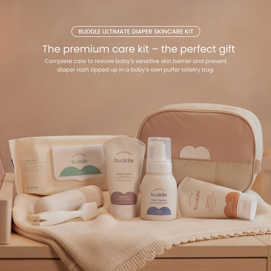 Diaper skincare kit on blanket with zip toiletry bag, wipes, and skincare bottles