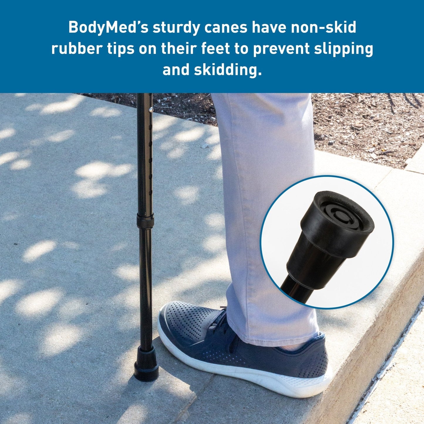 Black aluminum offset cane by BodyMed with non-slip rubber tip, shown beside a person's foot on pavement, close-up detail highlighted.