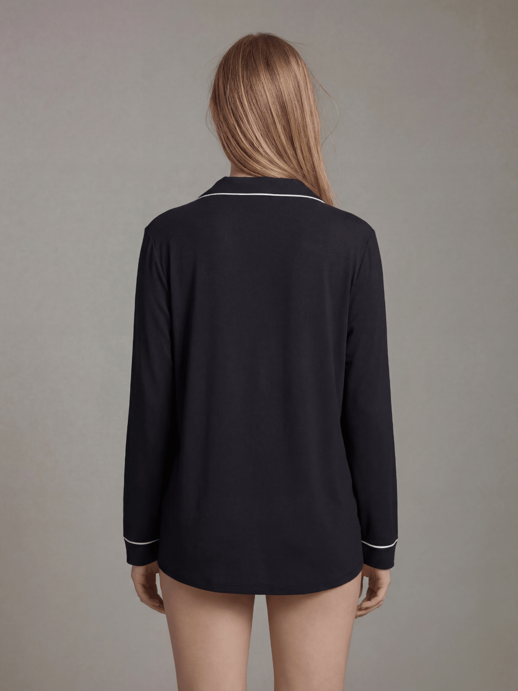Black button-down pajama top back view with white piping along seams