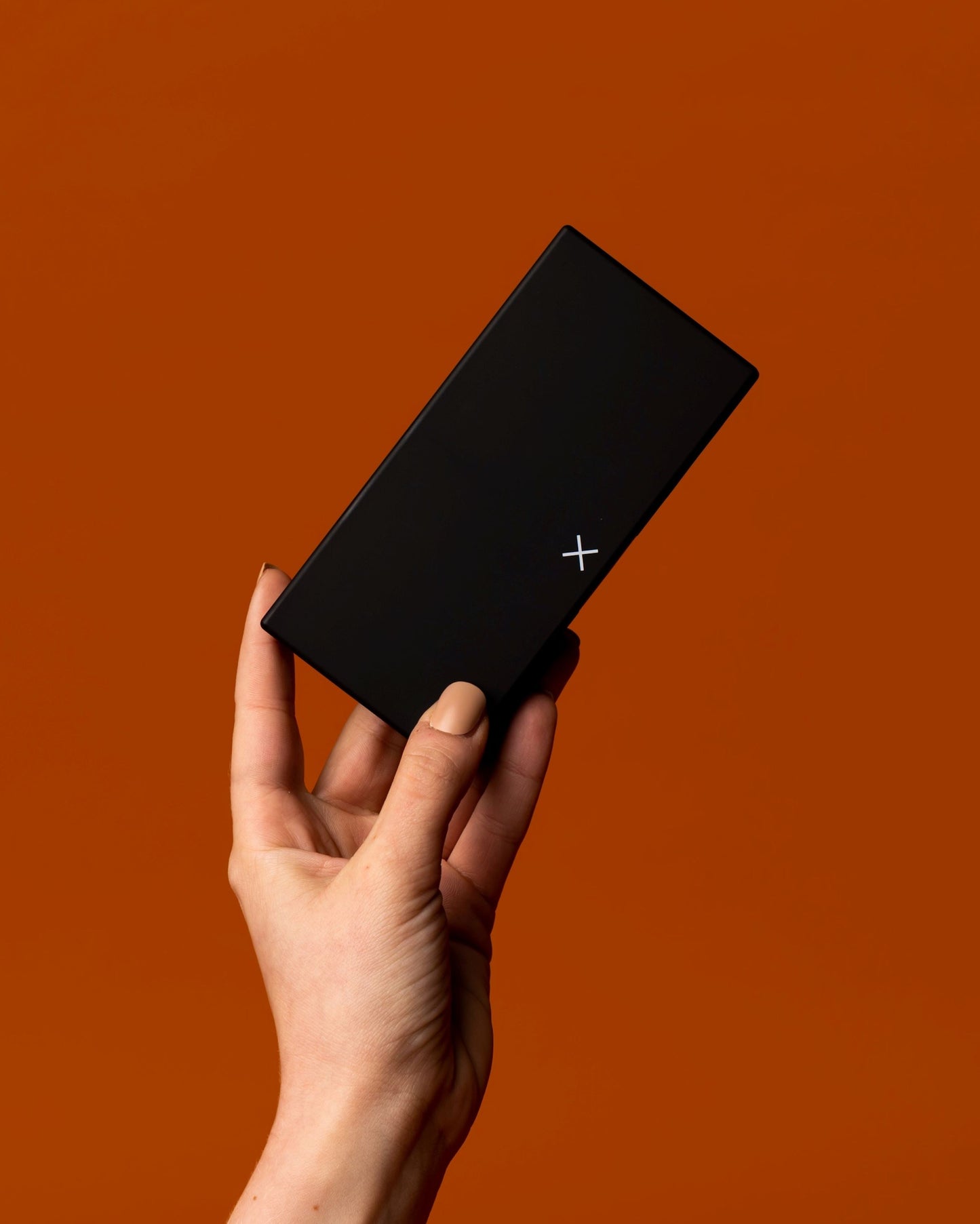 Closed black pill box in hand, rectangular shape with small X logo