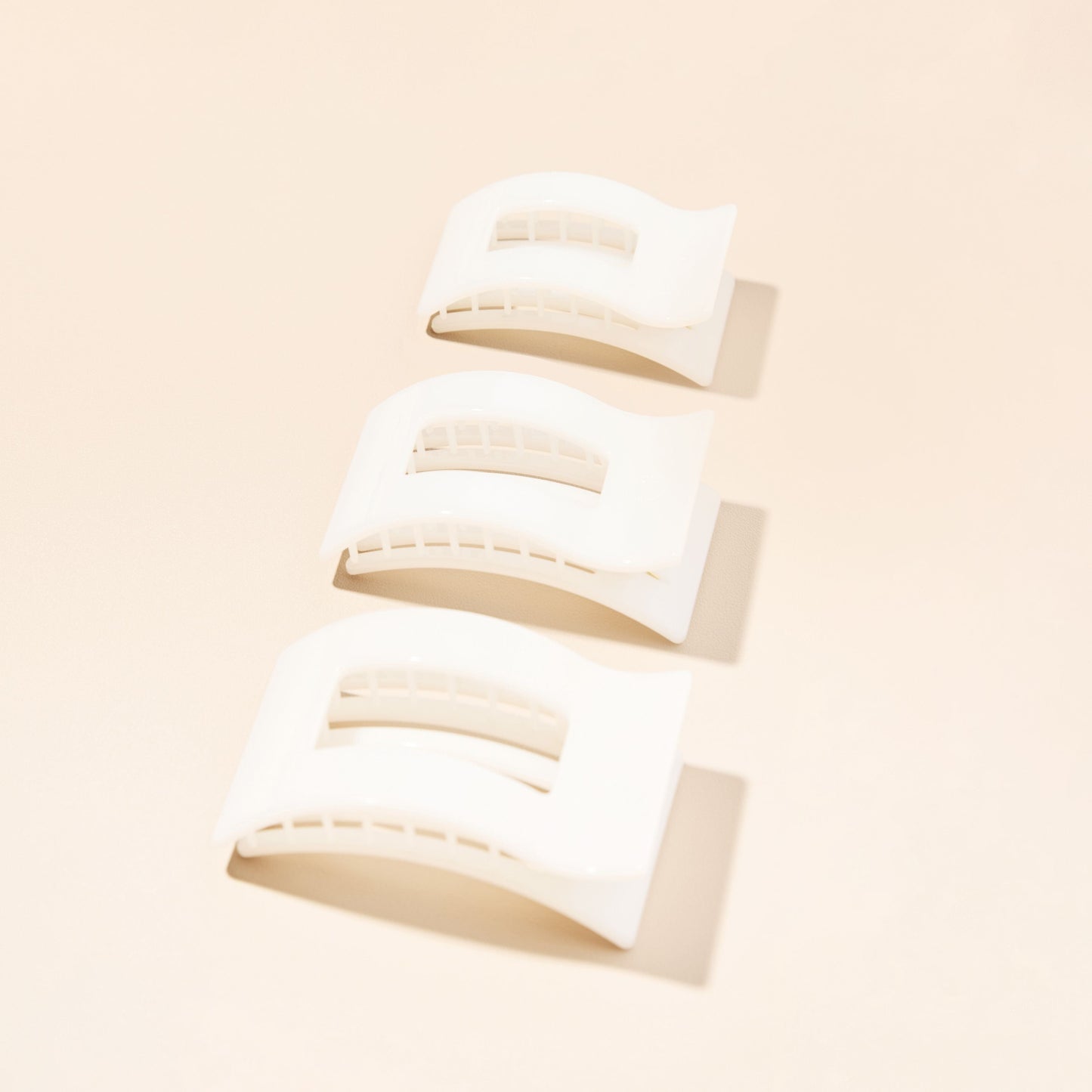 Multiple small white rectangle hair clips, shown from different angles