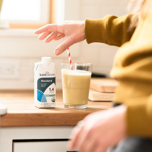 Kate Farms Standard 1.4 vanilla nutrition shake carton with a glass of vanilla drink