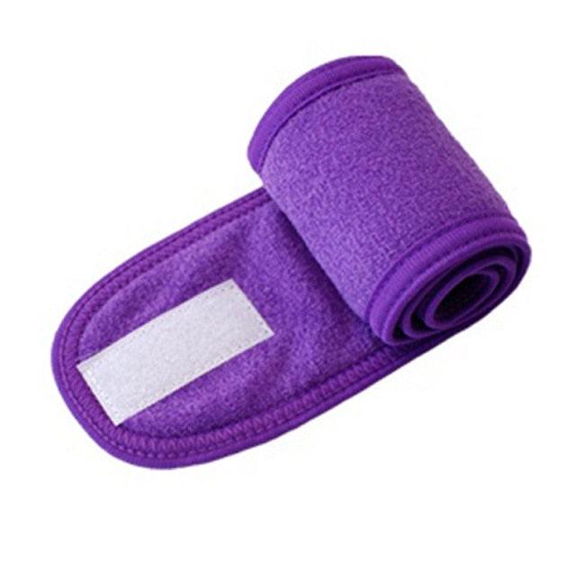Purple terry toweling headband with white patch, rolled face-wash accessory.