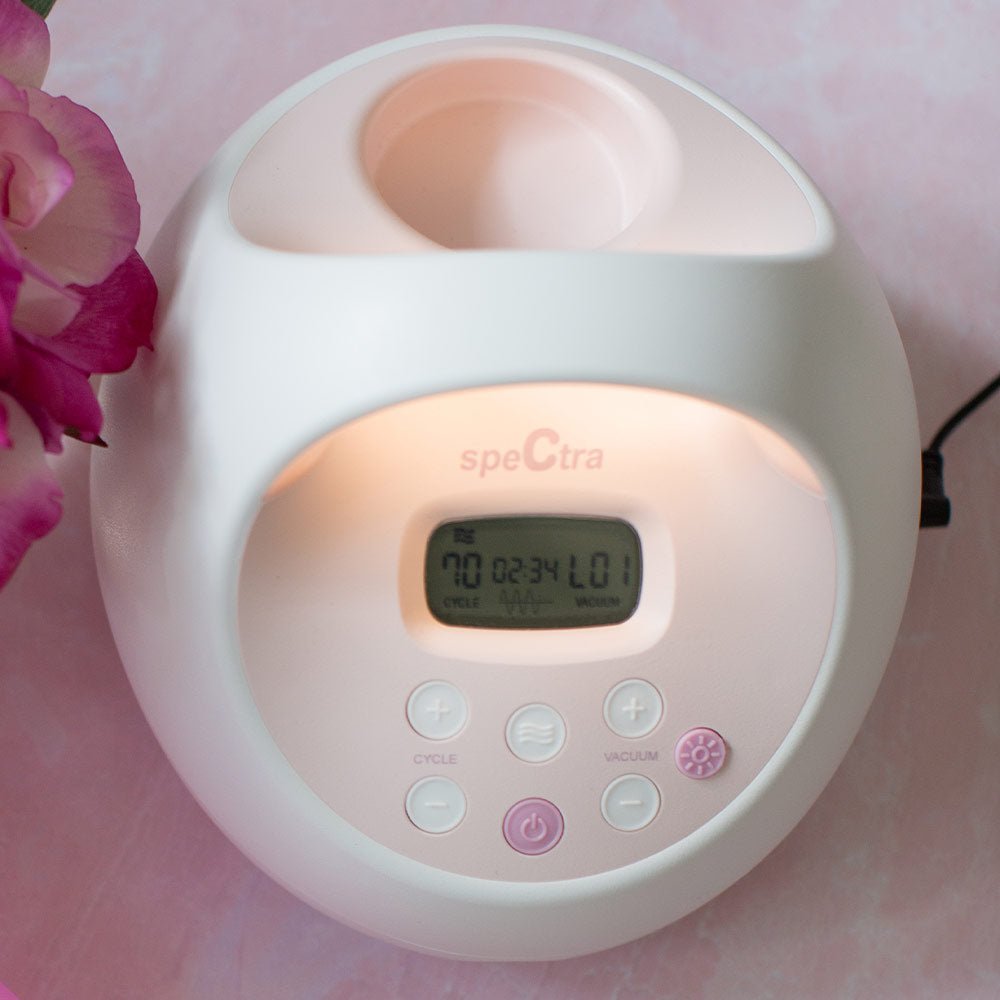 Close-up of breast pump LCD display and control buttons on white and pink unit