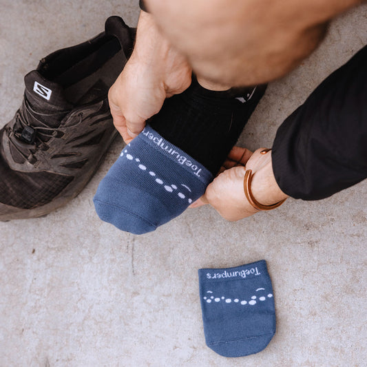 Men's toe-bumper socks in blue, being pulled over a black running shoe