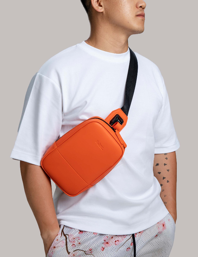 Man wearing a white tshirt with an orange cross body bag