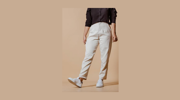 A woman wearing slip on white sneakers, elastic waist white pants and a navy blue sweatshirt