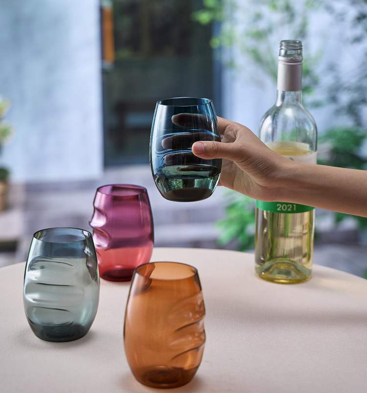 Four wine indestructable glasses with finger indents for easier grip. A hand is holding one glass up.