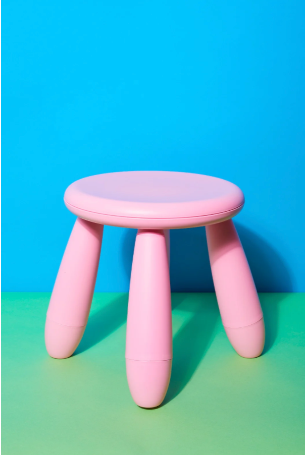 Pink stool in front of a green and blue background