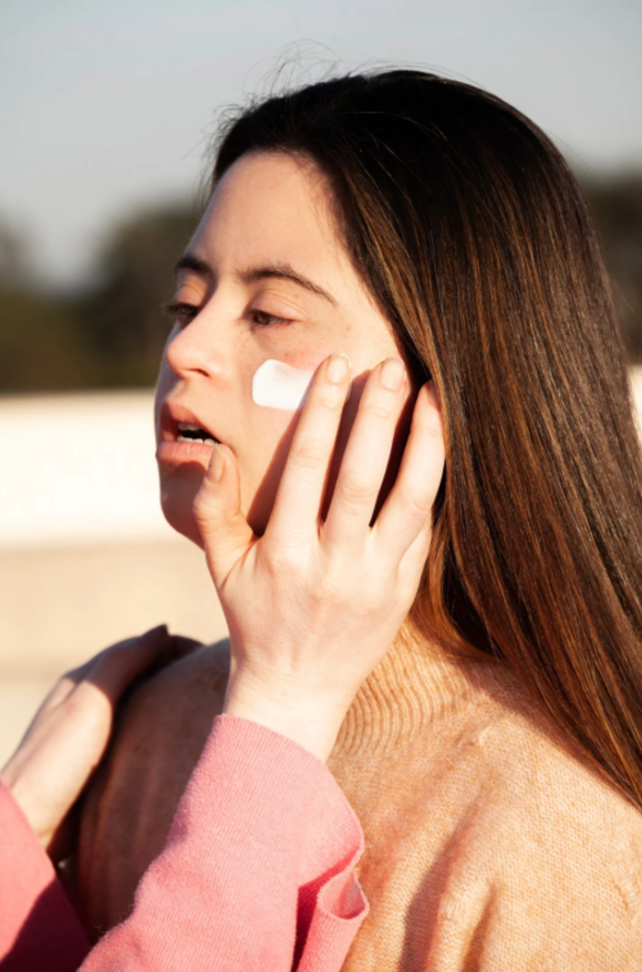 Woman with down syndrome applying sunscreen to her face