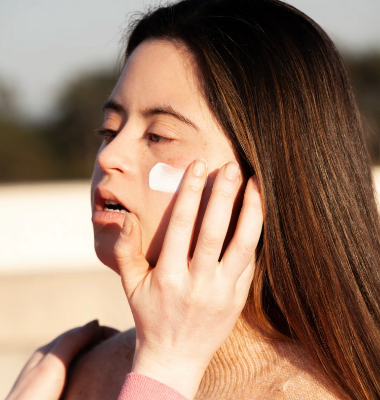 Woman with down syndrome applying sunscreen to her face