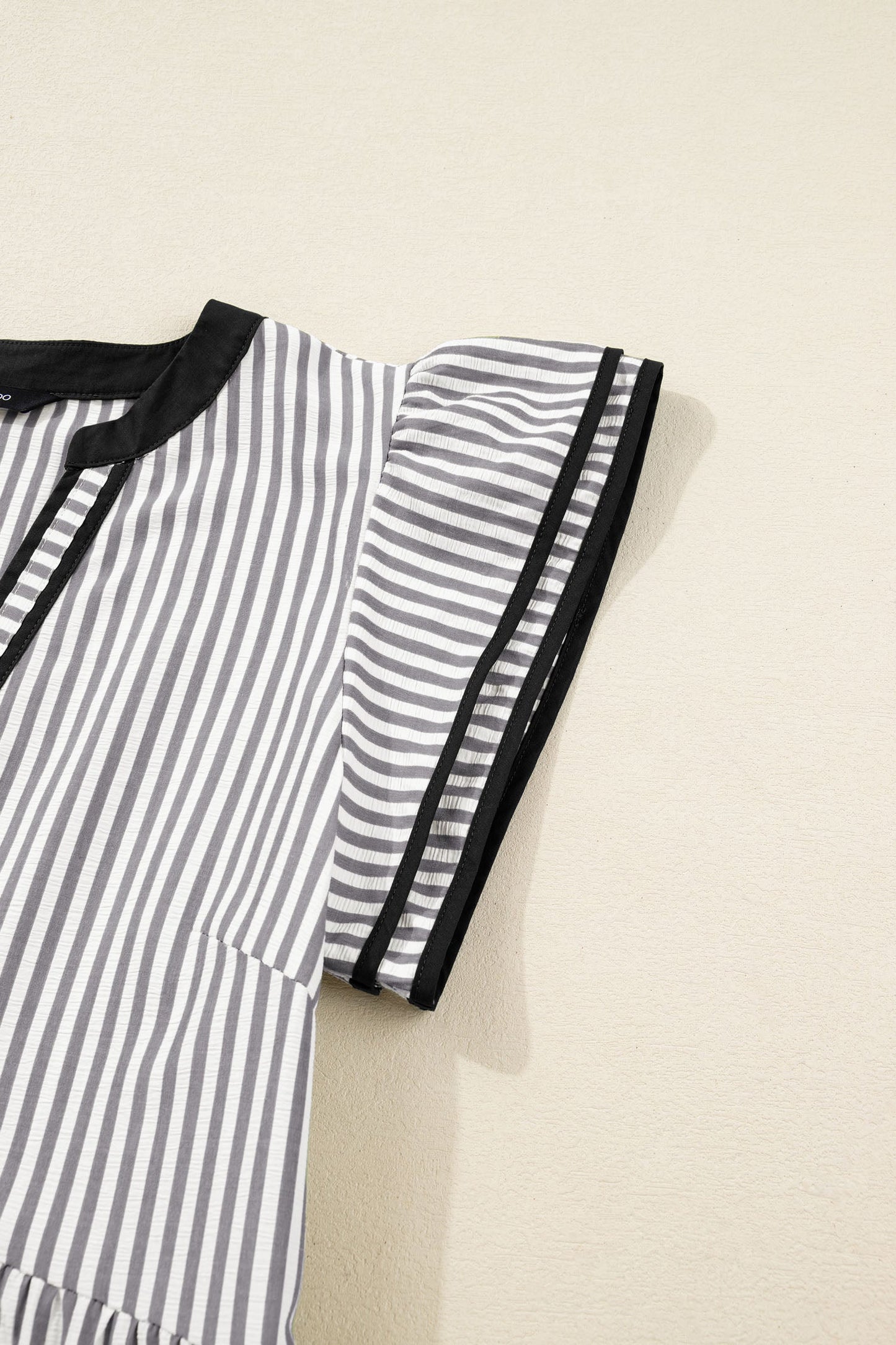 Striped dress side detail with black-trimmed short sleeves and tier seam