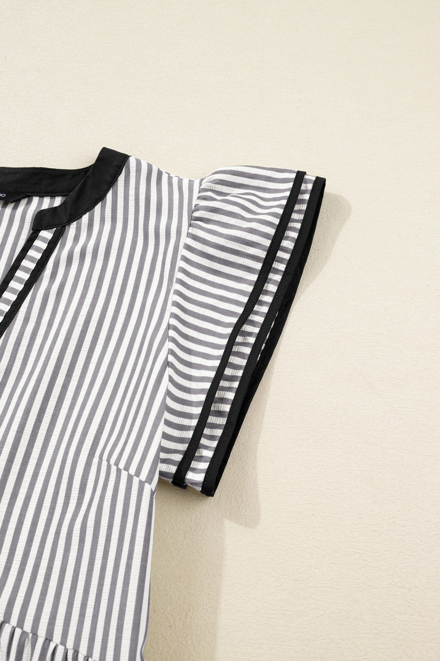 Striped dress side detail with black-trimmed short sleeves and tier seam