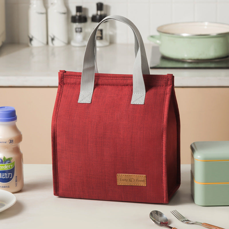 Red insulated lunch bag with light gray handles and tan logo label patch