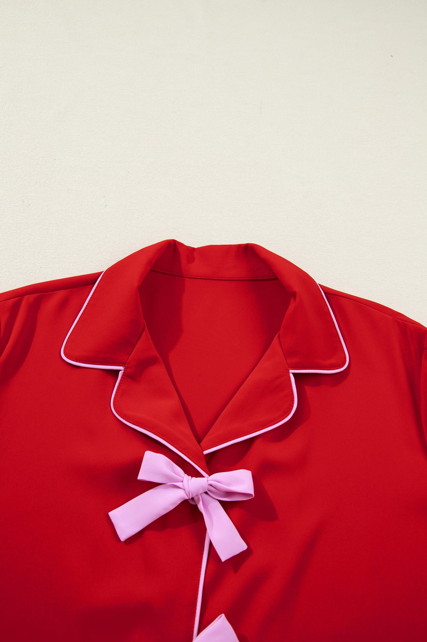 Red pajama top close-up: notched collar with contrast piping and central bow-tie detail