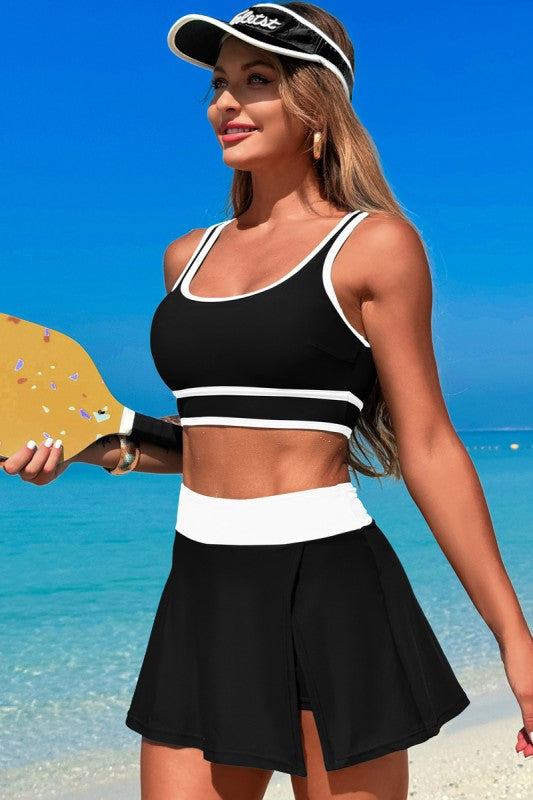 Black two-piece swimsuit with white-trim crop top and high-waisted skirt