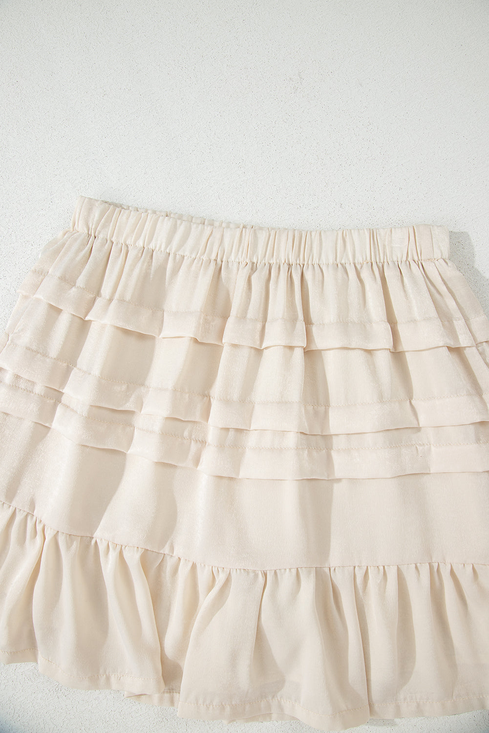 Beige tiered mini skirt top with elastic waistband and stacked ruffle tiers