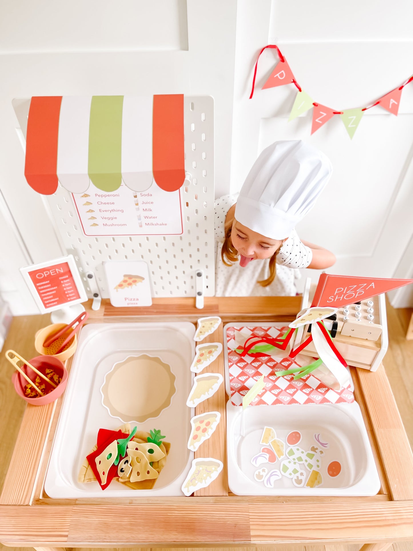 Pizza shop play kit with menu board, open sign, and child arranging pizza pieces