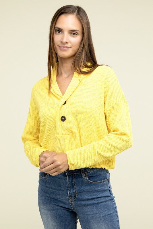 Yellow textured pullover top with V-neck, button closure, chest pocket, long sleeves
