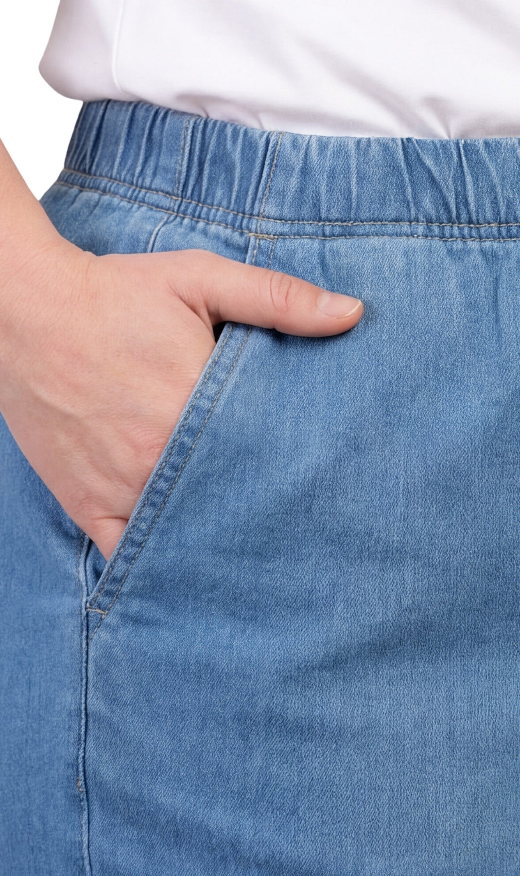Close-up of a person wearing blue jeans with a white shirt underneath.