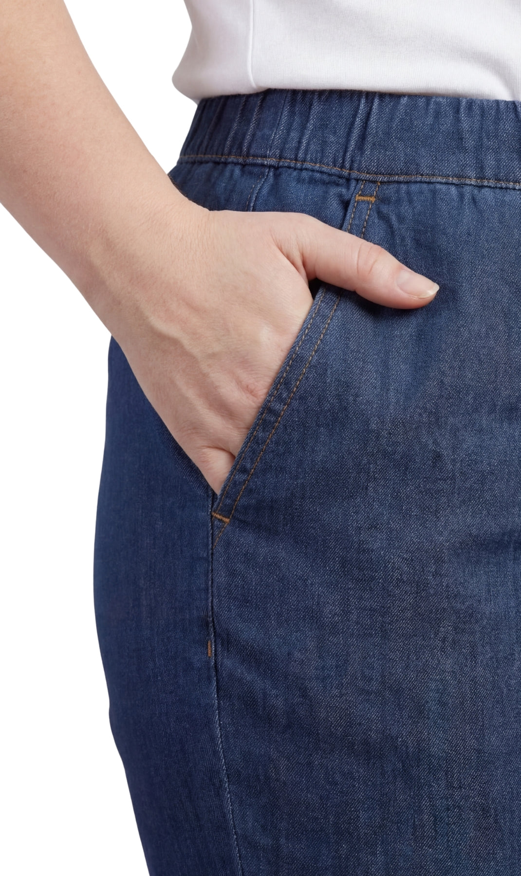 Person wearing blue jeans with a white shirt, hand in pocket on a white background