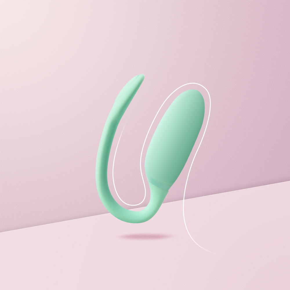 Mint green silicone kegel exercise device with loop handle, resting on surface