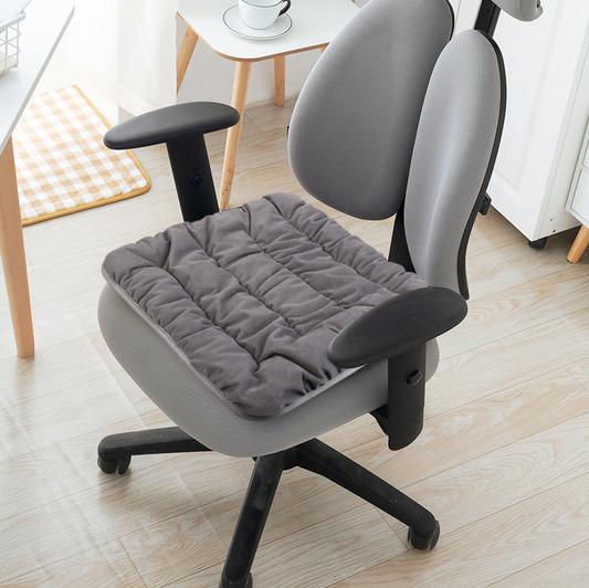 Grey electric heating pad on chair seat with black control cable