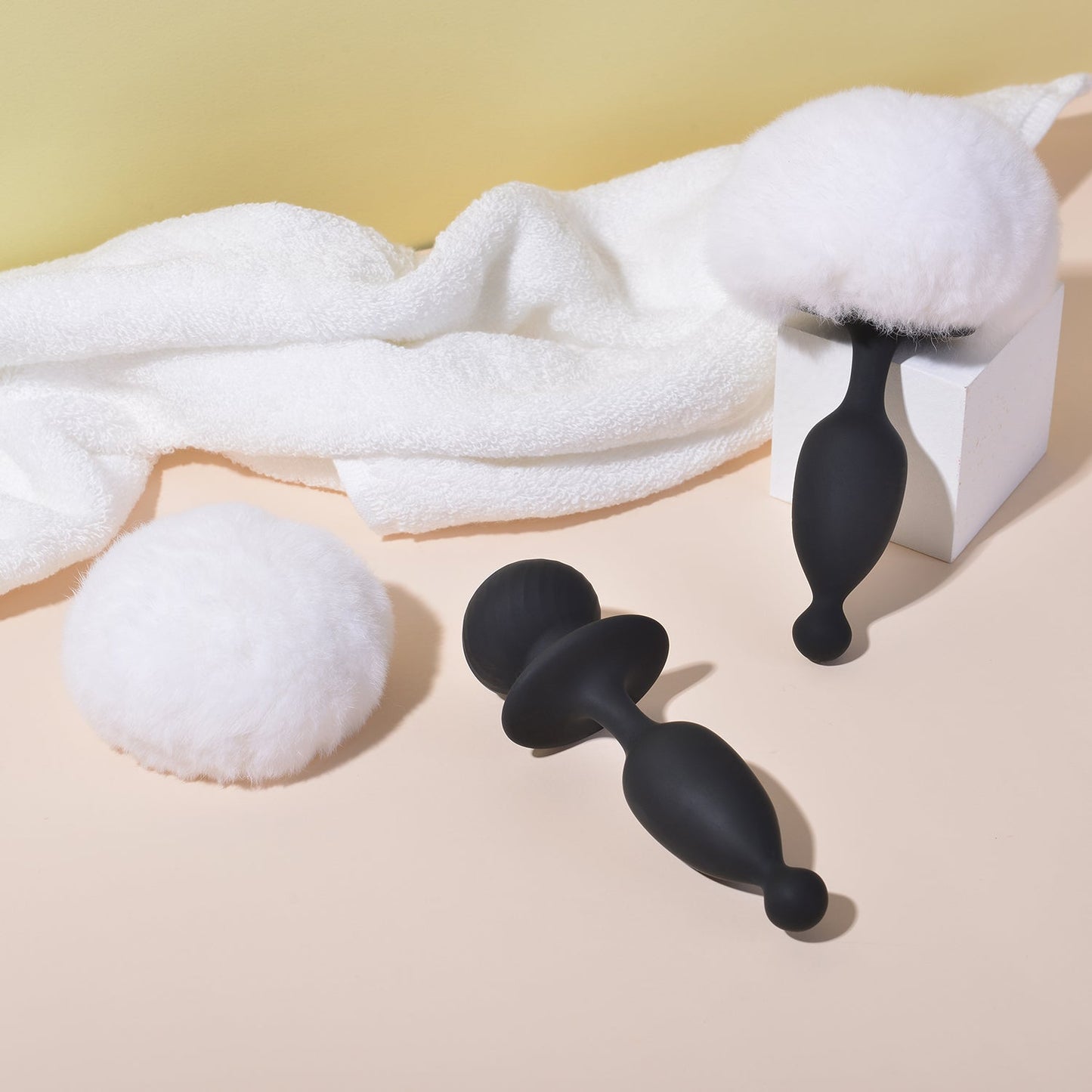 Black silicone bunny tail toy with white plush tail and towel accessory
