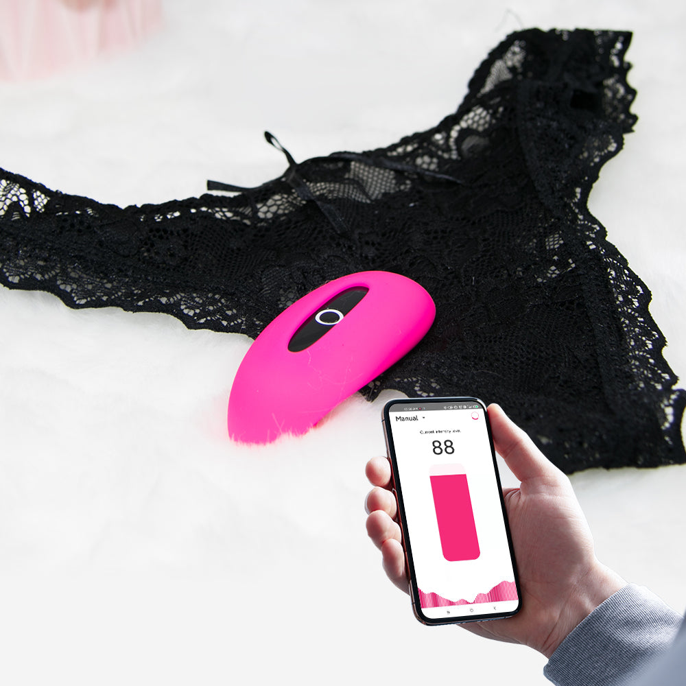 Pink silicone personal massager on black lace with smartphone app display