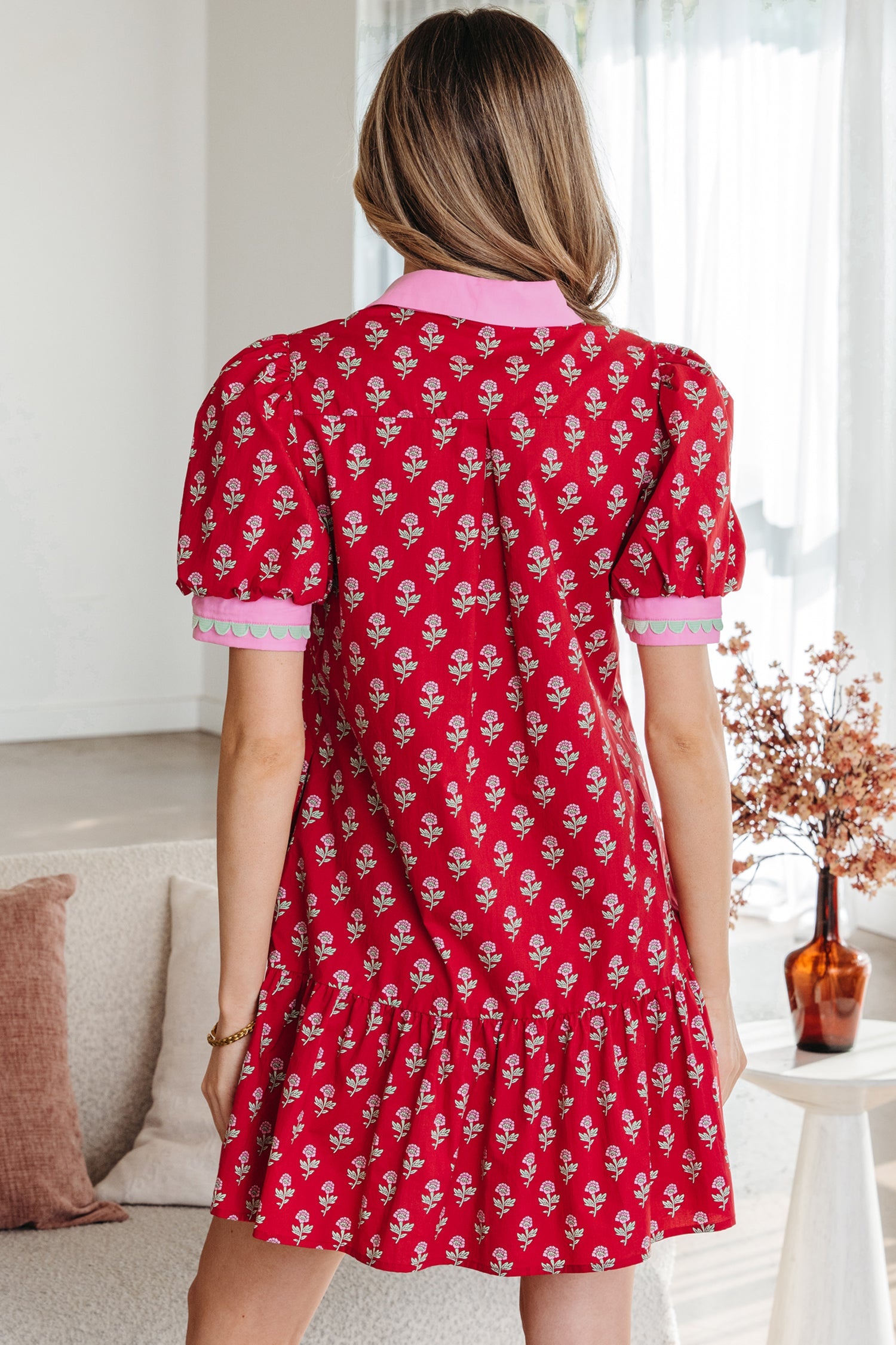 Red mini dress back view with pink-trim sleeves and gathered skirt hem.