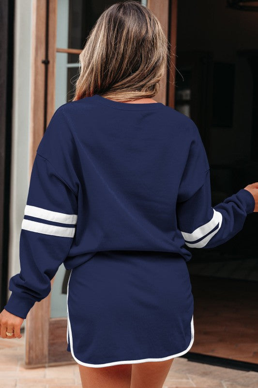Back view of navy pullover and mini skirt set with striped sleeve detail.