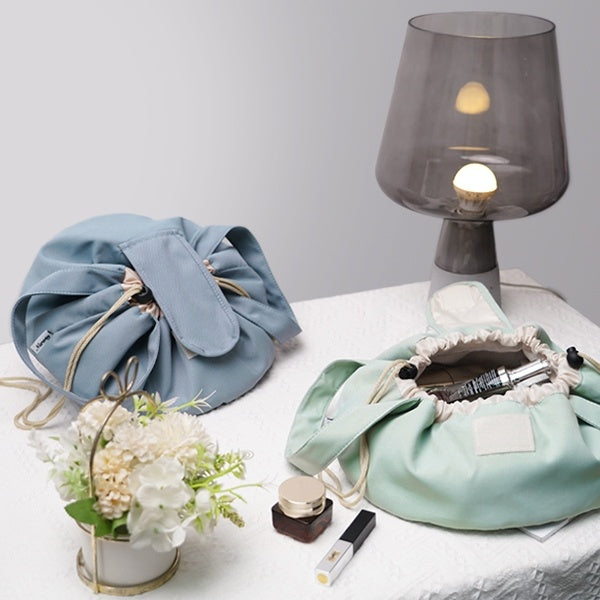 Sky blue drawstring makeup bag, open barrel top showing toiletries and inner lining