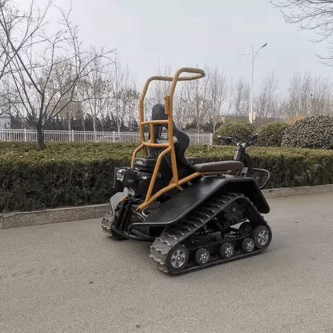 All-terrain electric wheelchair with tan handlebar, black seat, and treaded track wheels
