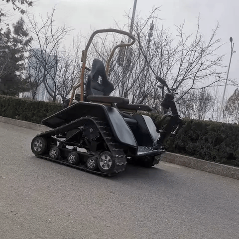Black electric wheelchair with front control handle and deep tread tracks for off-road