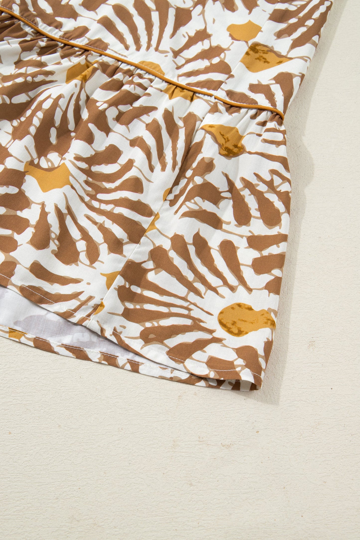 Loose long plus dress fabric with tan and white abstract print and stitched hem edge.