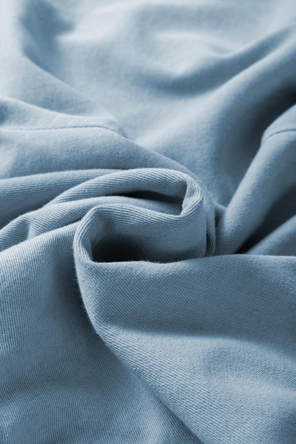 Washed chambray fabric close-up with soft folds, blue