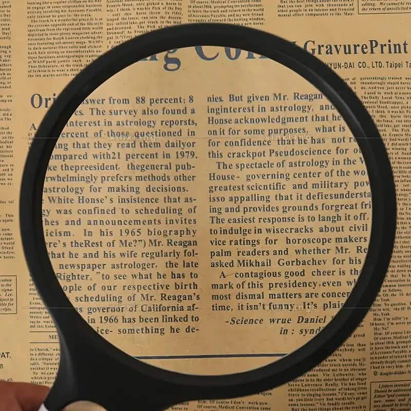 Handheld magnifier lens enlarging printed text on paper