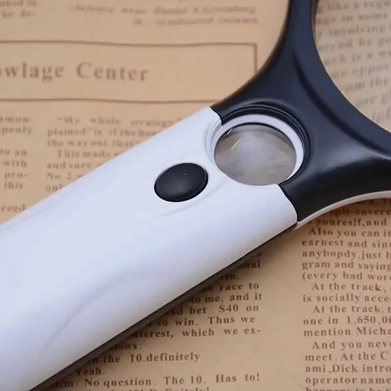 Close-up of handheld magnifier with round lens and black control button on white body