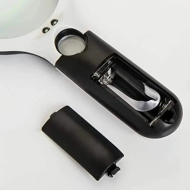 Handheld LED magnifier with battery cover detached and lens facing up
