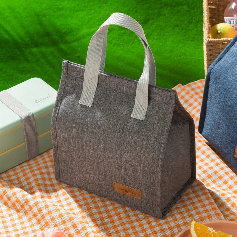 Insulated lunch bag in dark gray with light gray handles and front label patch